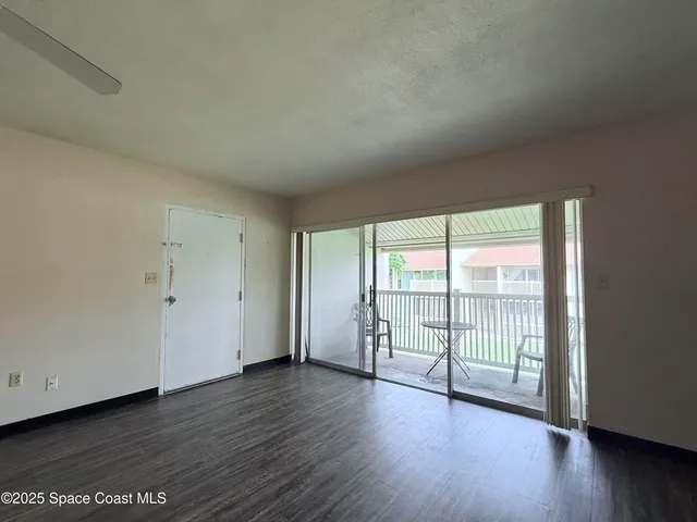 a view of a big room with wooden floor and windows