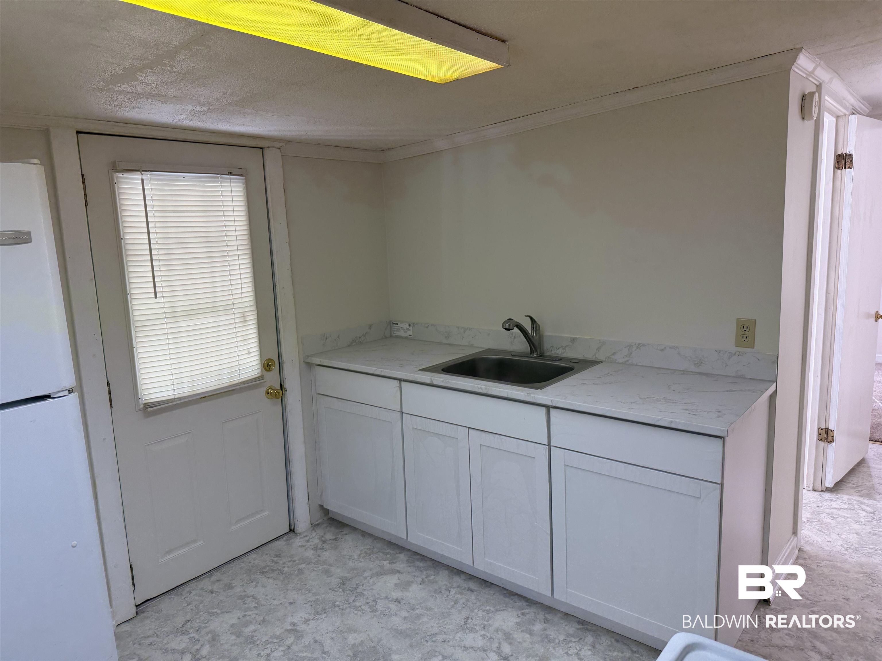 3630 Highway 29 Brewton, AL 36426 - Photo 13 of 13 Kitchen with light stone counters, sink, white fridge, and white cabinetry