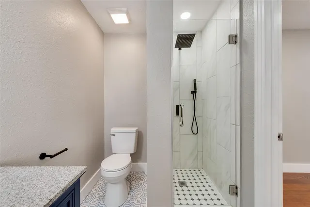a bathroom with a granite countertop shower and a toilet