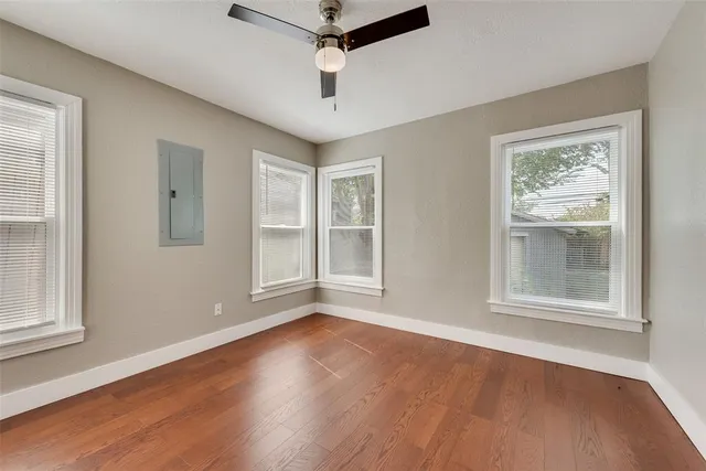 an empty room with wooden floor chandelier and windows
