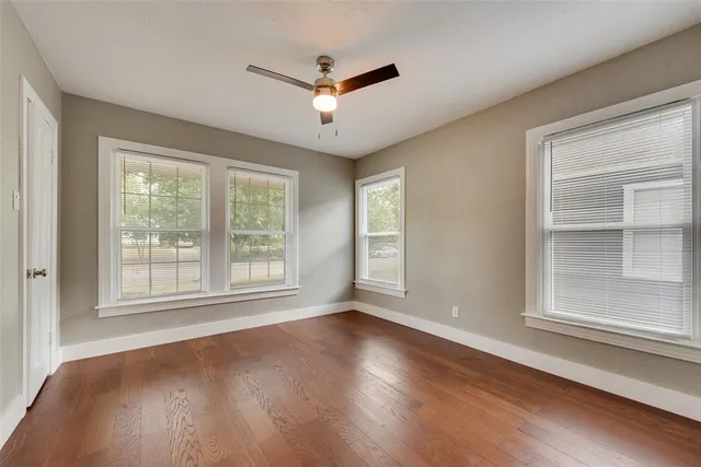 a view of empty room with wooden floor and fan