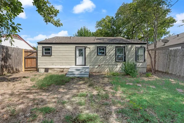 a backyard of a house with plants and large tree