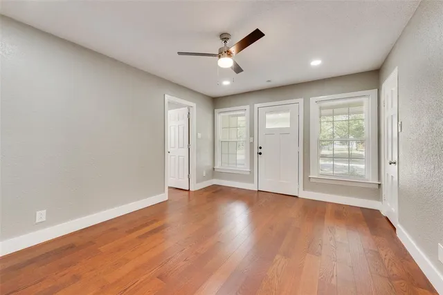 a view of an empty room with wooden floor and a window