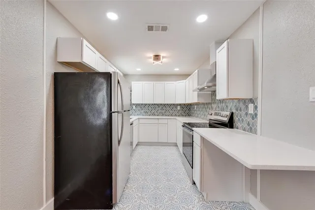 a kitchen with a refrigerator and white cabinets