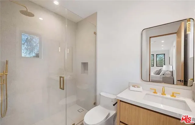 a bathroom with a toilet sink vanity granite and shower
