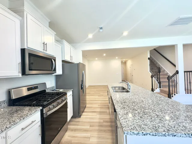 a large kitchen with kitchen island granite countertop a sink and stainless steel appliances