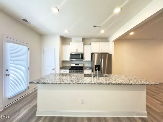 a large kitchen with granite countertop a large counter top stainless steel appliances and cabinets