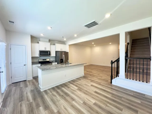 a large white kitchen with kitchen island a sink dishwasher a stove and a refrigerator with wooden floor