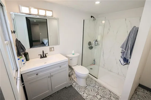 a bathroom with a sink a toilet a mirror and shower