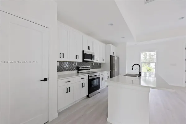 a kitchen with stainless steel appliances granite countertop white cabinets a refrigerator a stove a sink and dishwasher