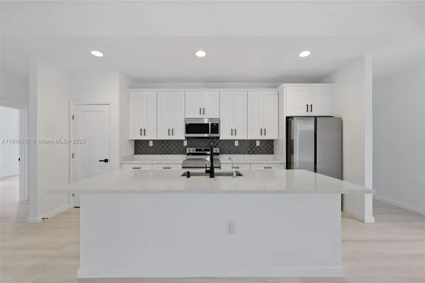 a kitchen with stainless steel appliances granite countertop a refrigerator a stove a sink and white cabinets