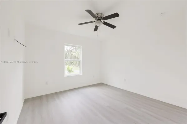 an empty room with a window and a fan