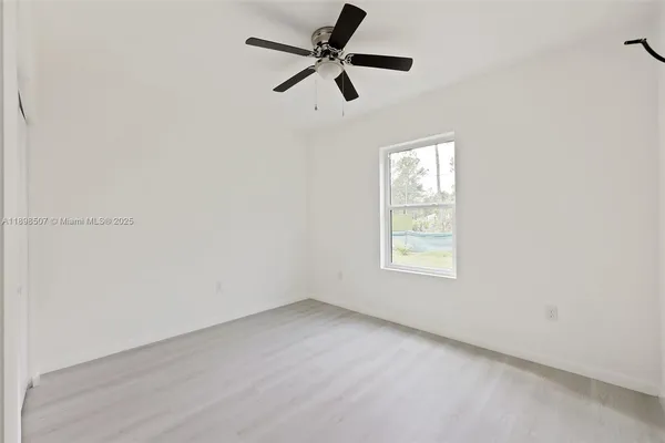 an empty room with a window and a fan