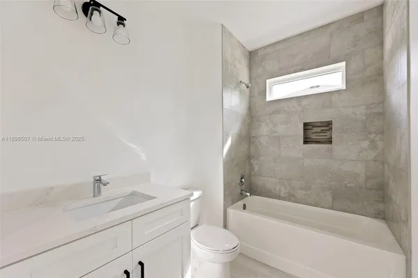 a bathroom with a granite countertop sink a toilet and bathtub