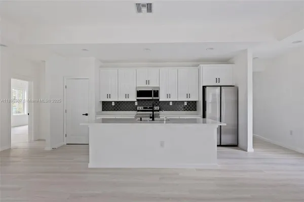 a kitchen with stainless steel appliances granite countertop a refrigerator sink and white cabinets