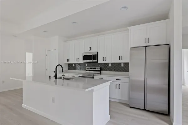 a kitchen with stainless steel appliances granite countertop a refrigerator sink and white cabinets