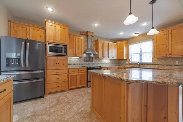 a kitchen with stainless steel appliances granite countertop a refrigerator a stove a sink and a microwave