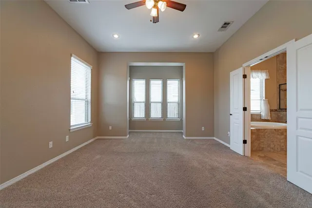 an empty room with chandelier fan and windows