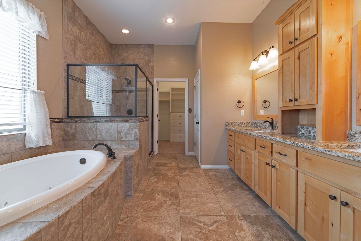 125 Walter Way Jarrell, TX 76537 - Photo 22 of 40 Bathroom featuring double vanity, a jetted tub, a spacious closet, and a shower stall