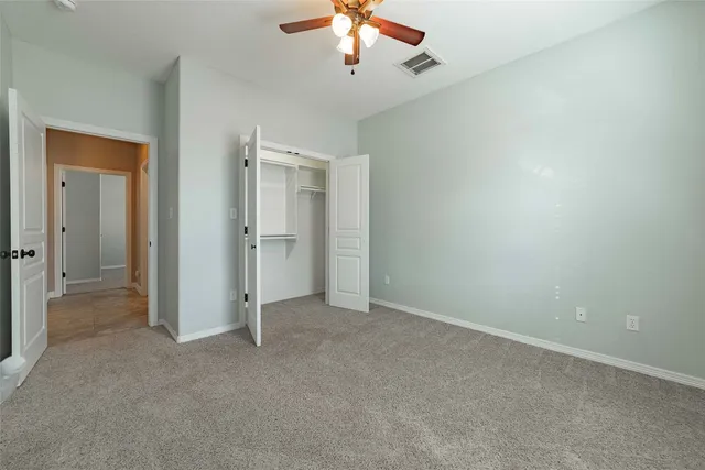 an empty room with closet and a ceiling fan