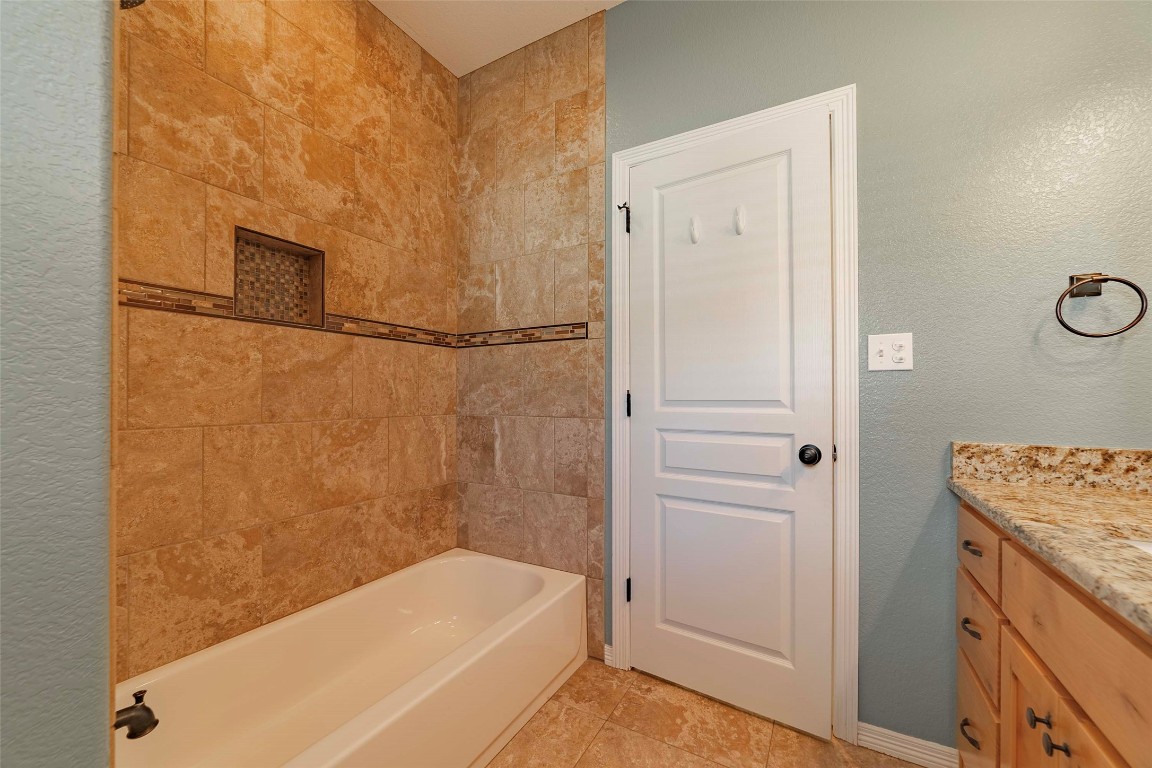 125 Walter Way Jarrell, TX 76537 - Photo 32 of 40 Full bathroom featuring vanity, bathing tub / shower combination, and a textured wall