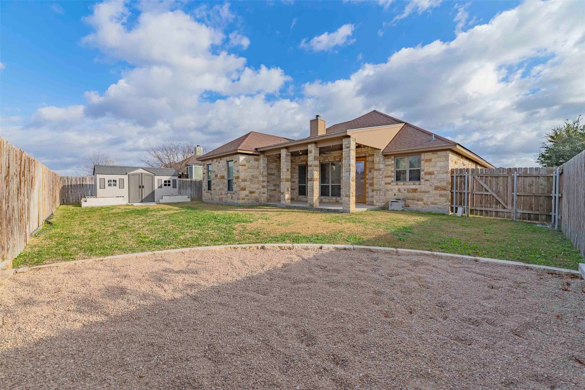 125 Walter Way Jarrell, TX 76537 - Photo 36 of 40 Rear view of house featuring a patio area, a fenced backyard, a chimney, and a storage shed