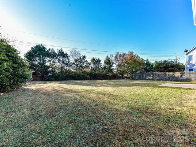 a view of yard with swimming pool and trees in the background