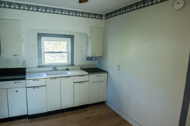 a kitchen with a sink cabinets and wooden floor