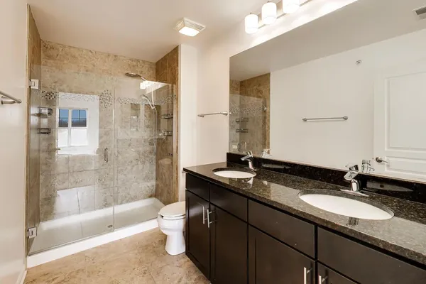 a bathroom with a granite countertop double vanity sink and mirror with bathtub