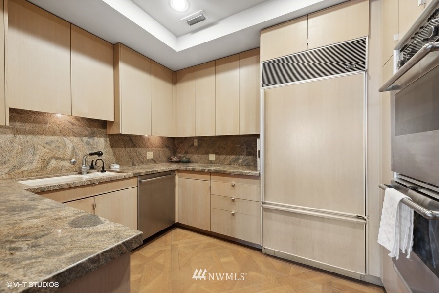 1301 Spring Street, Unit 30J Seattle, WA 98104 - Photo 9 of 40 a kitchen with a sink refrigerator and cabinets