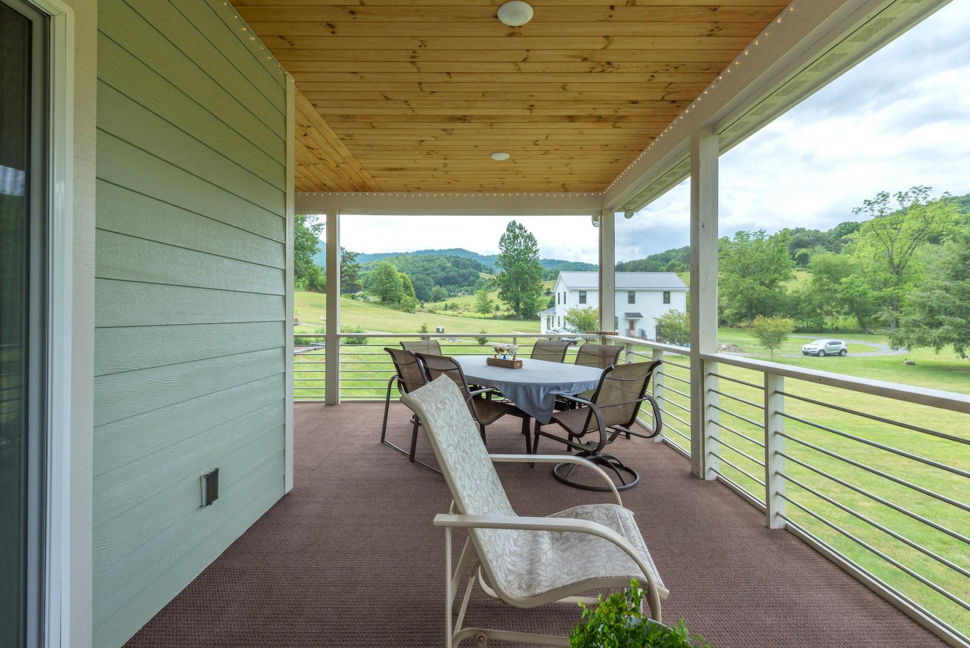 750 Iron Tree Drive Clyde, NC 28721 - Photo 25 of 40 a view of a patio with table and chairs and wooden floor