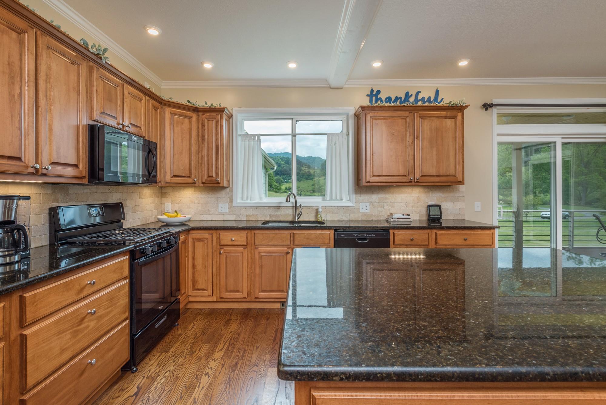 750 Iron Tree Drive Clyde, NC 28721 - Photo 30 of 40 a kitchen with granite countertop a stove a sink and a microwave