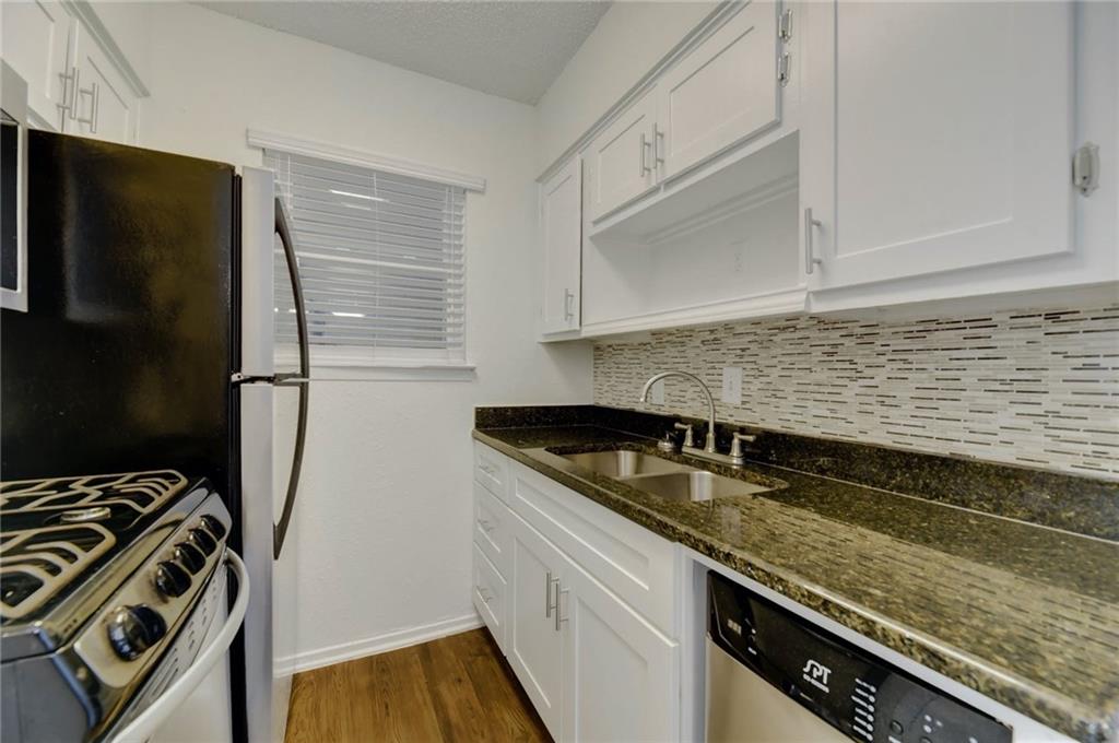 A compact kitchen with sleek black appliances and contrasting white cabinetry provides practical living.