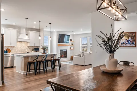 a living room with furniture kitchen view and a wooden floor