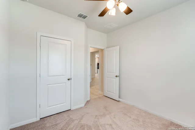 an empty room with chandelier fan and closet area