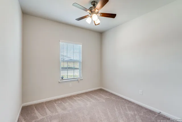 an empty room with chandelier fan and closet area