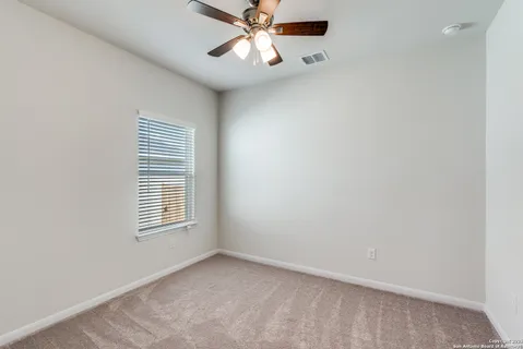 an empty room with windows and fan