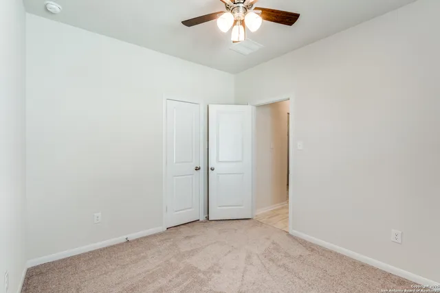 an empty room with a chandelier fan and windows