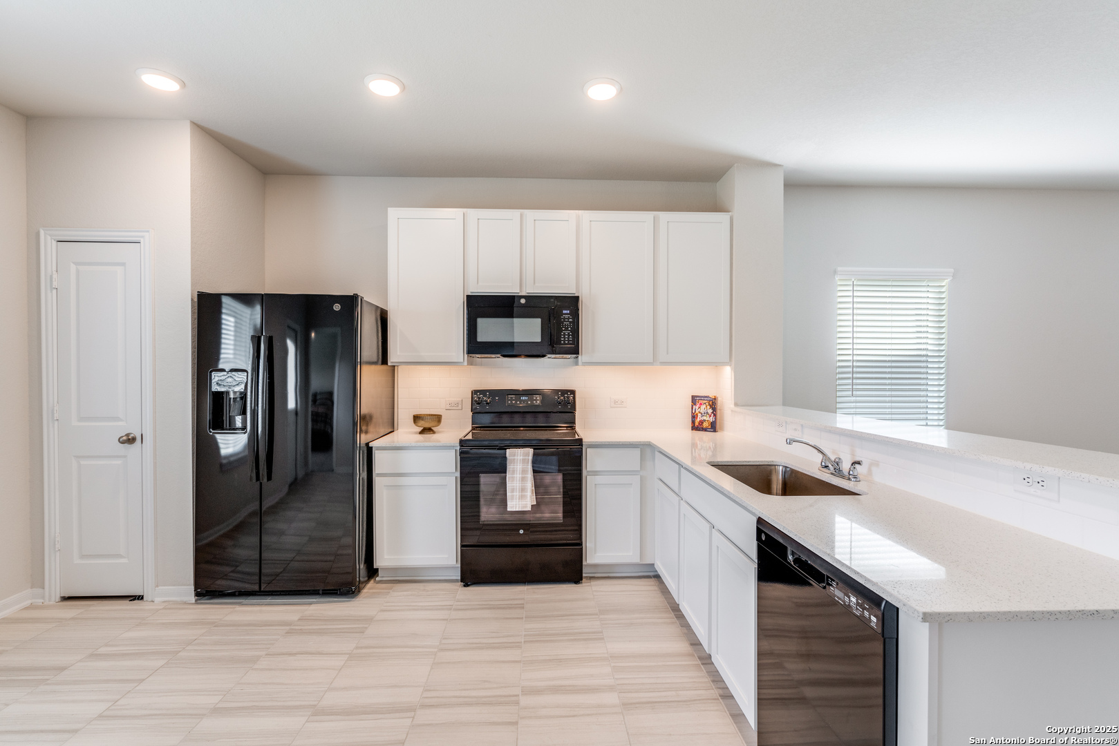 8931 Hazel Birch Elmendorf, TX 78112 - Photo 7 of 21 a kitchen with a sink a refrigerator and cabinets