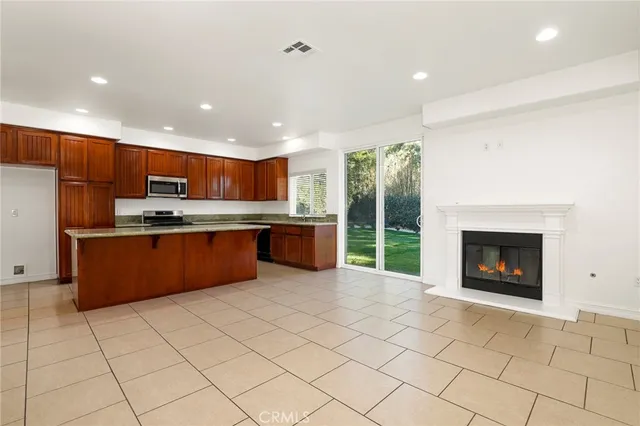 a kitchen with stainless steel appliances granite countertop a stove top oven a sink dishwasher and a fireplace with wooden floor