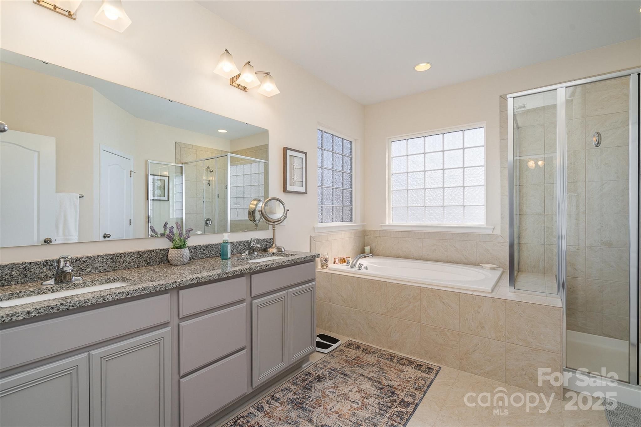 6187 Cloverdale Drive Tega Cay, SC 29708 - Photo 22 of 36 a spacious bathroom with a granite countertop tub sink and mirror