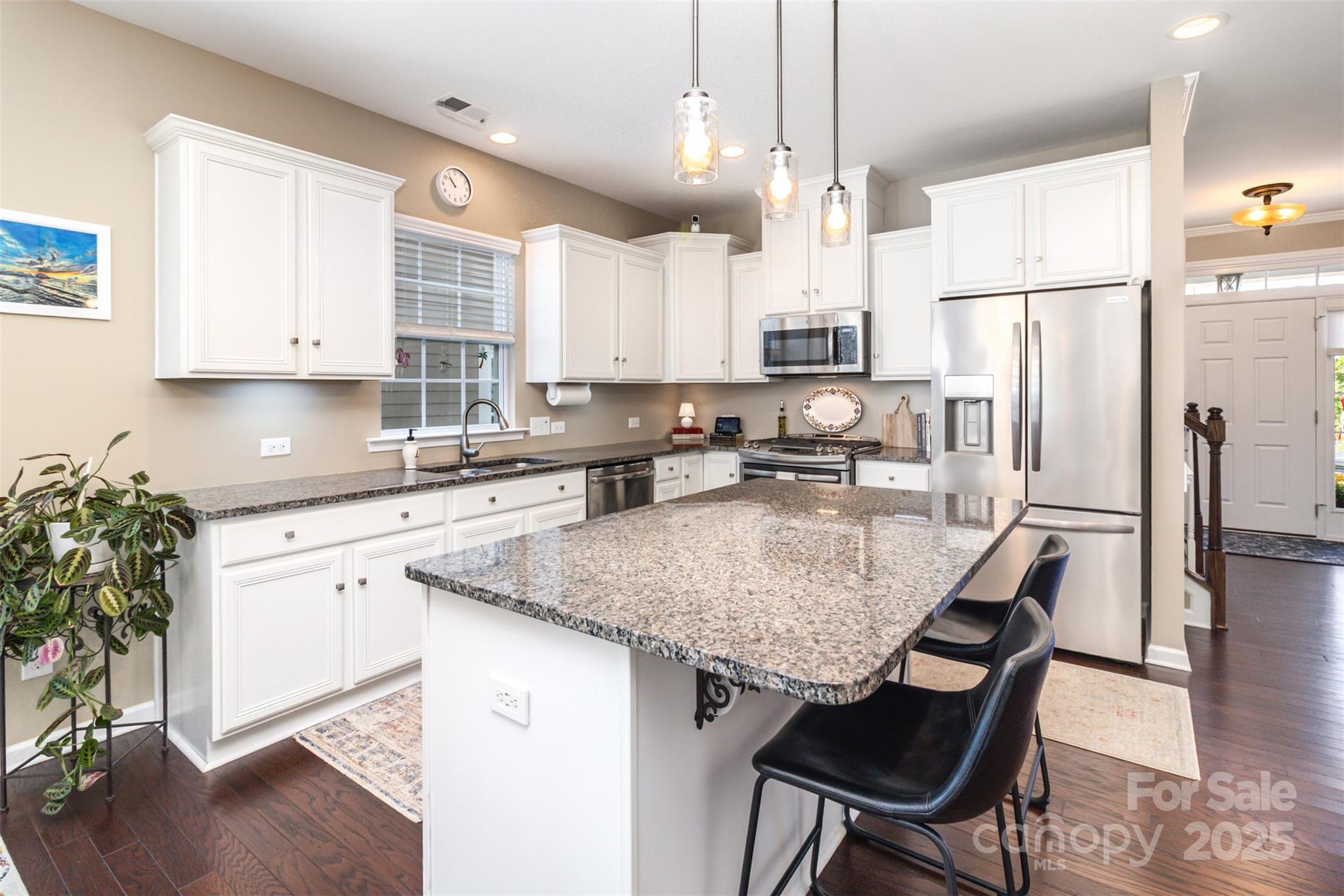 6187 Cloverdale Drive Tega Cay, SC 29708 - Photo 10 of 36 a kitchen with stainless steel appliances granite countertop a sink a stove a refrigerator a center island and a wooden floor
