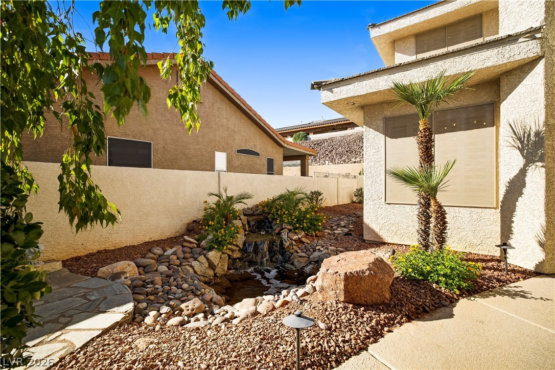 1135 Calico Ridge Drive Henderson, NV 89011 - Photo 7 of 86 An inviting xeriscaped front yard with a charming waterfall feature and mature palm trees creates an attractive curb appeal.