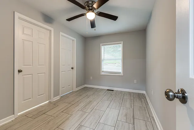 a view of a hallway with a chandelier fan and windows