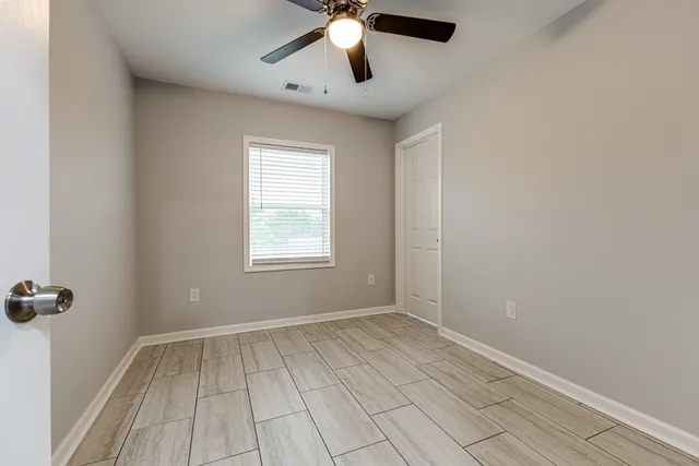 an empty room with wooden floor and windows