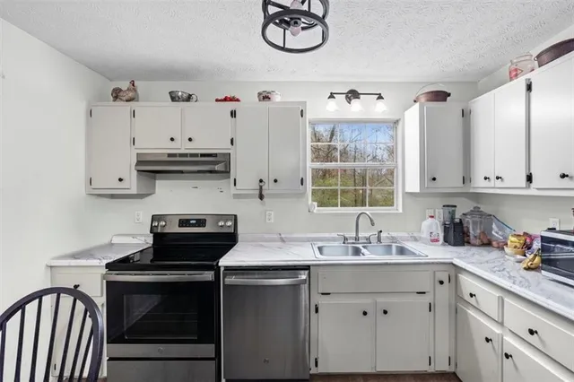 a kitchen with stainless steel appliances granite countertop a dining table chairs refrigerator and microwave