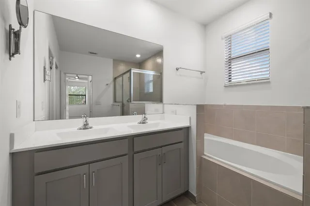 a bathroom with a double vanity sink mirror and bathtub