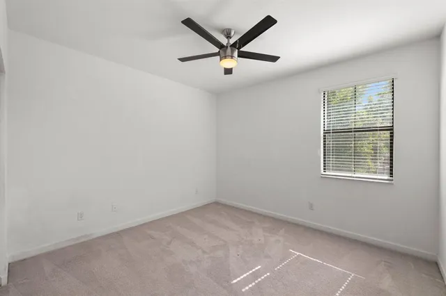 an empty room with ceiling fan and windows