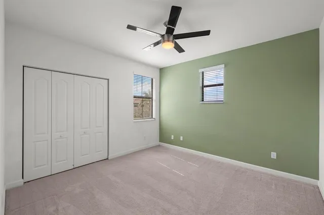 a view of a livingroom with a ceiling fan & windows