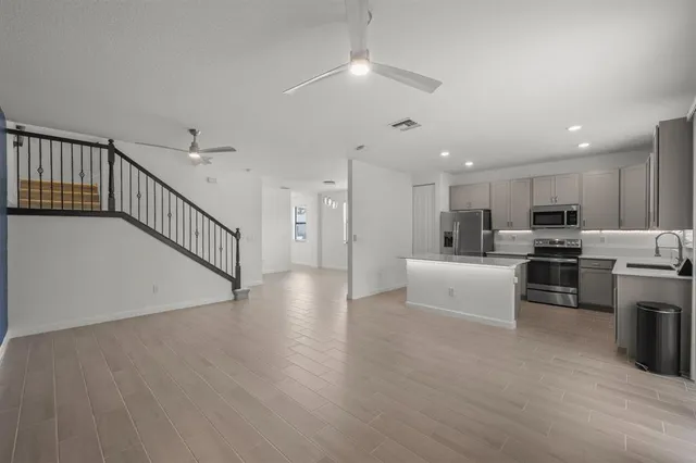 a view of kitchen with microwave a stove a refrigerator cabinets and wooden floor